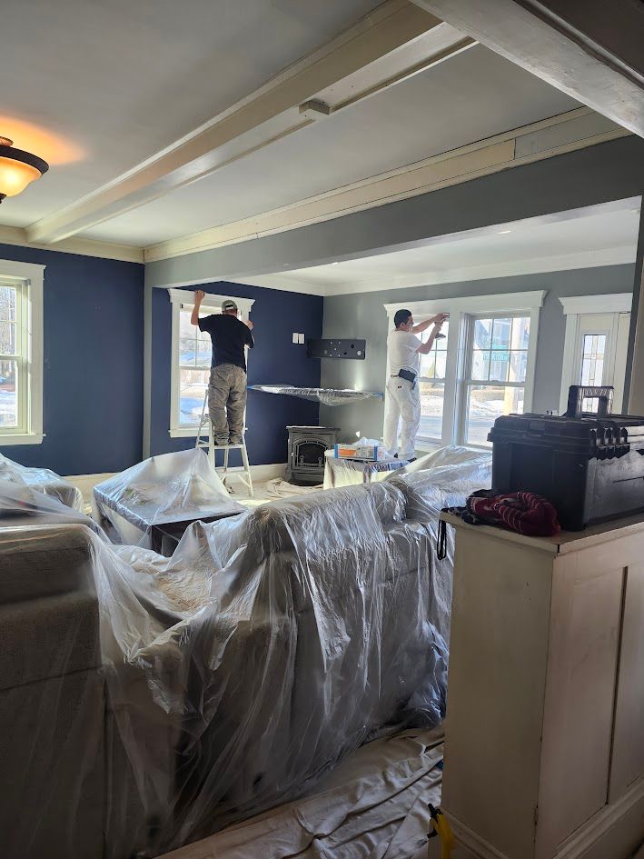Workers covering furniture with plastic in a living room under renovation