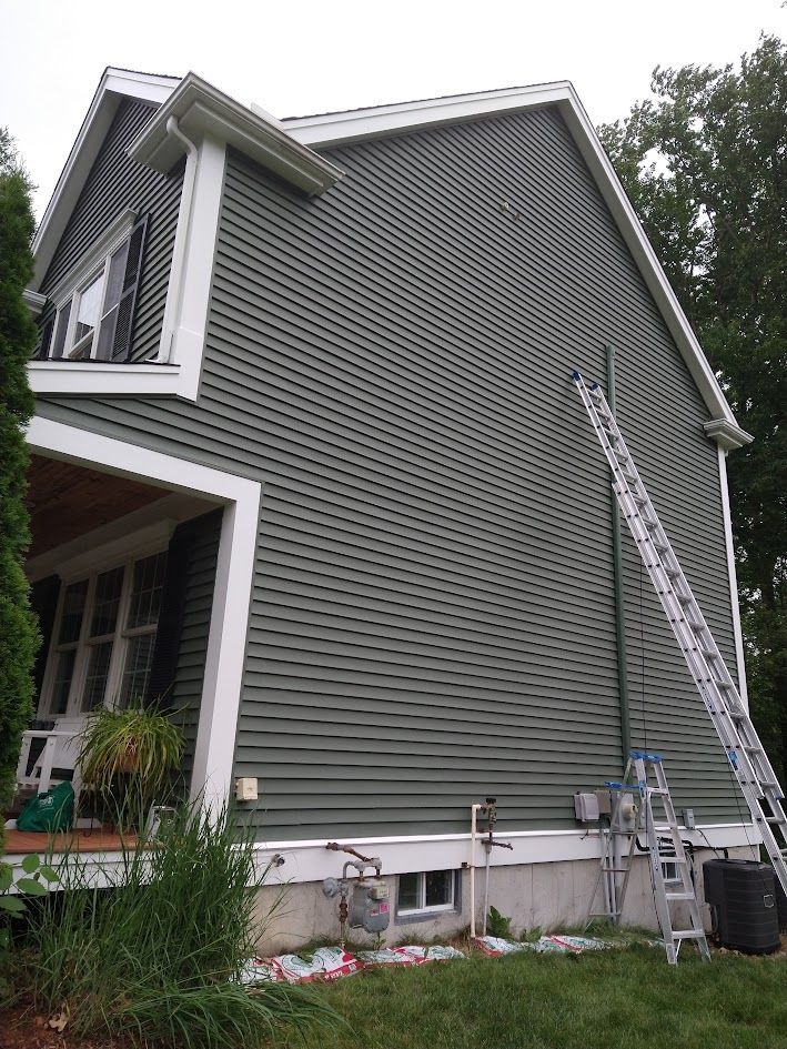 Gray house exterior with white trim and ladders against the wall
