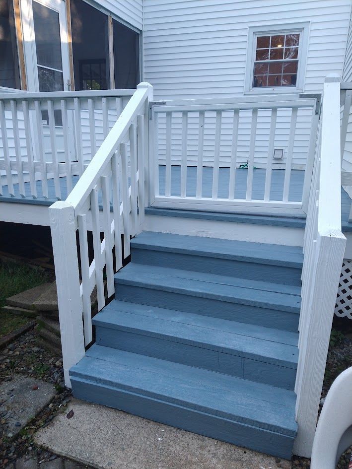 White porch stairs with gray steps and railings leading to a house entrance