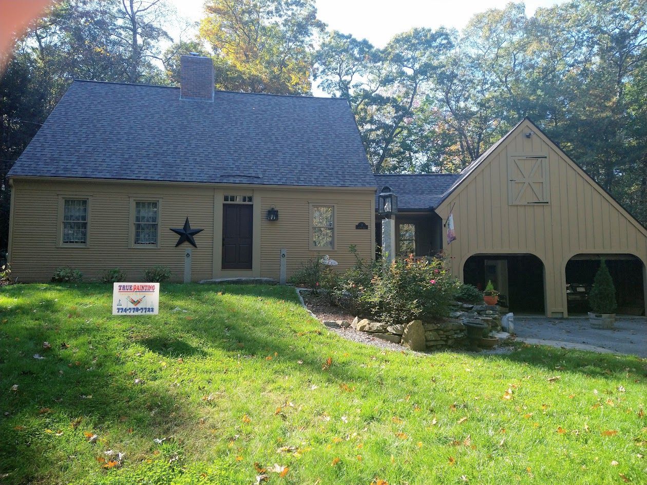 Small beige house with a detached garage, star decor, and a red-and-white sign in the front yard.