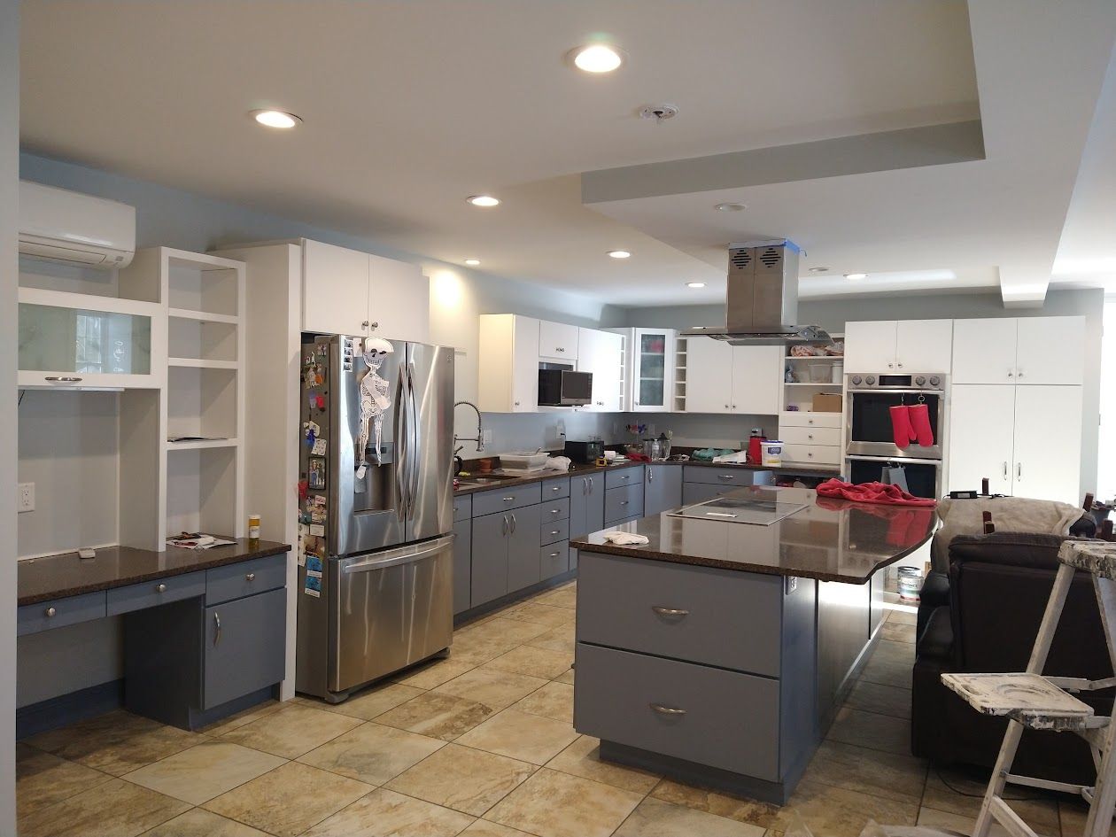 Modern kitchen with stainless steel appliances, gray cabinets, and a central island under recessed lights