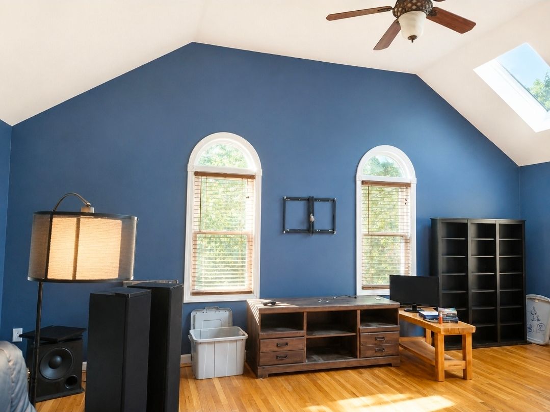 Blue-walled room with arched windows, ceiling fan, and furniture along the wall.
