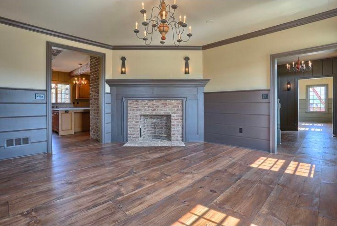 Empty living room with hardwood floors, a gray fireplace, and sunlight streaming through windows