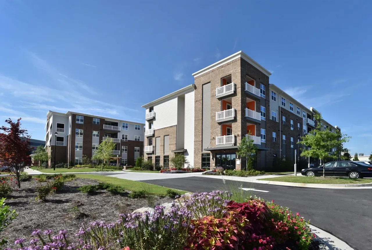 Exterior view of a modern apartment building with landscaped grounds and parking.