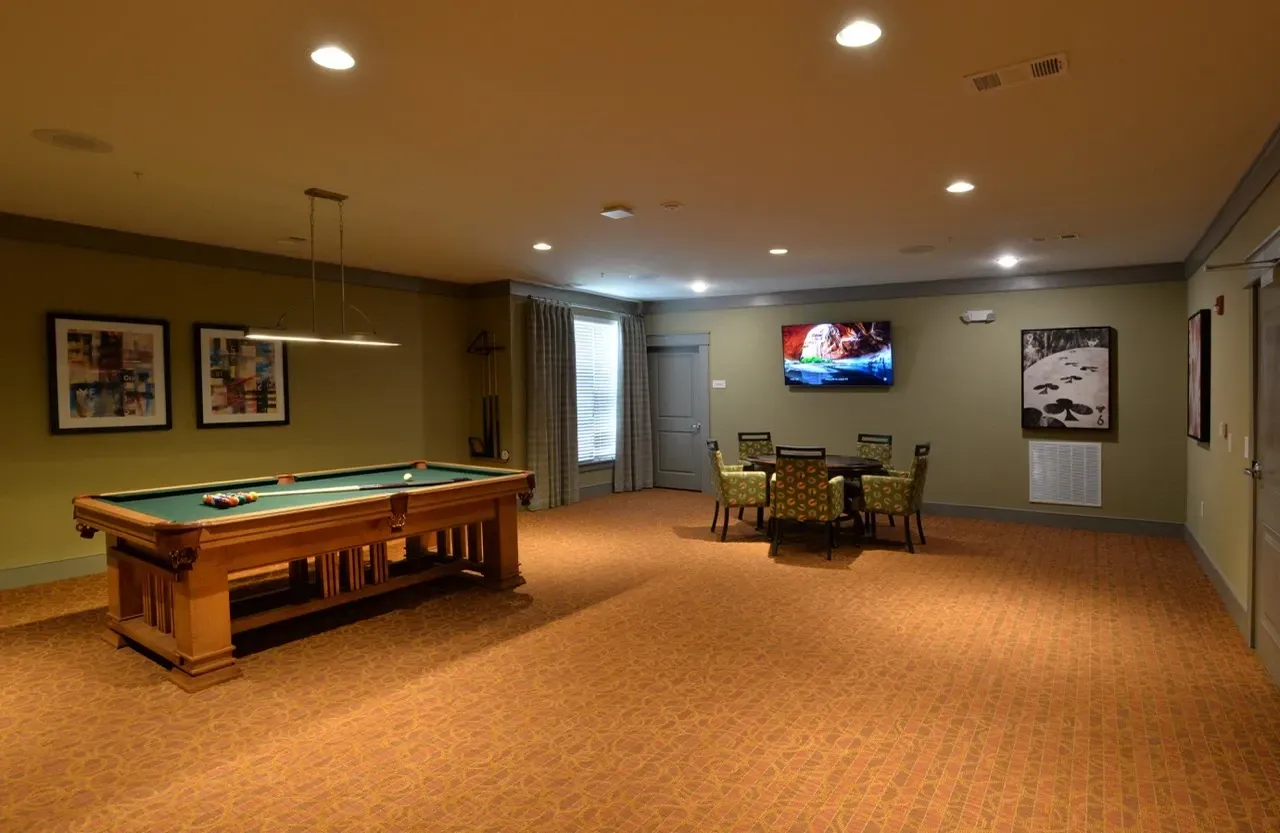 Indoor community game room with a pool table, seating, and a TV.