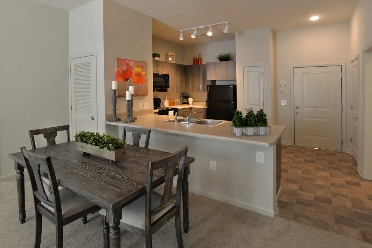 Open-concept kitchen and dining area in an apartment with an island and entry hallway.