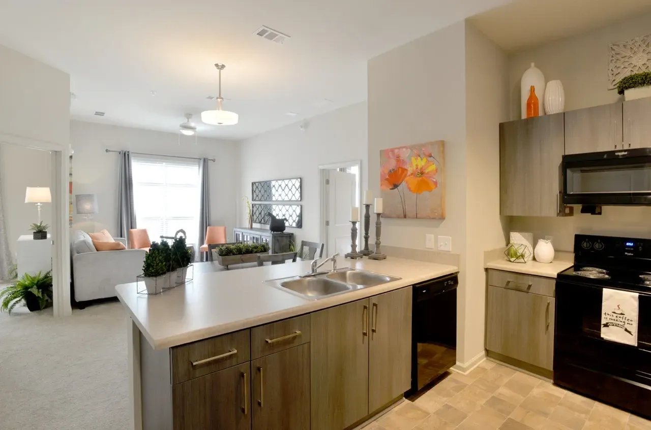 Open-concept kitchen with island and living area in an apartment.