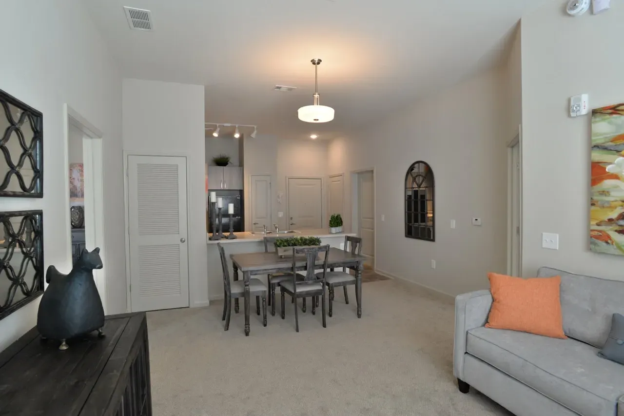 Open-concept living and dining area with a gray sofa and dining table in a modern apartment.