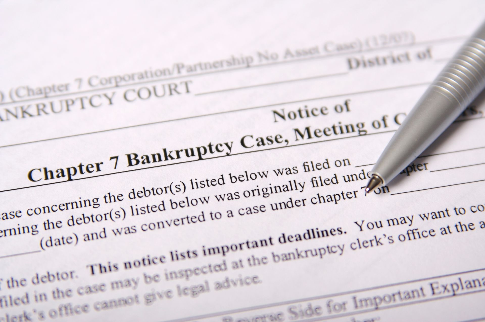 A pen sits on top of a chapter 7 bankruptcy court form
