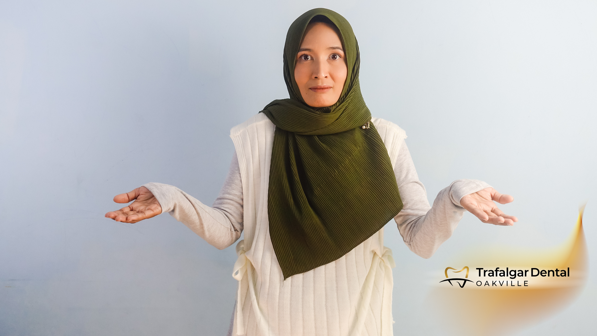 A woman wearing a hijab and a white sweater is shrugging her shoulders.