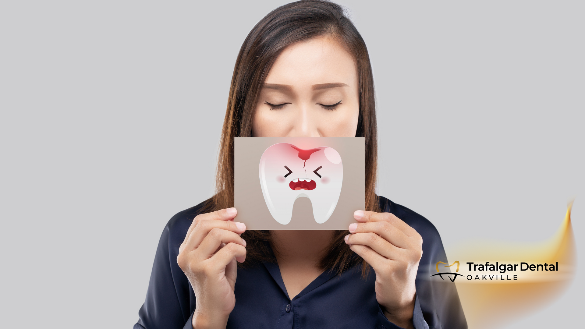 A woman is holding a card with a tooth on it in front of her mouth.