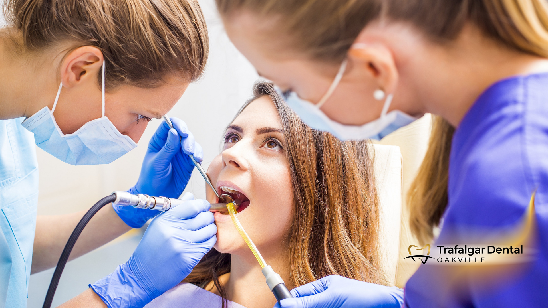 A woman is getting her teeth examined by two dentists.