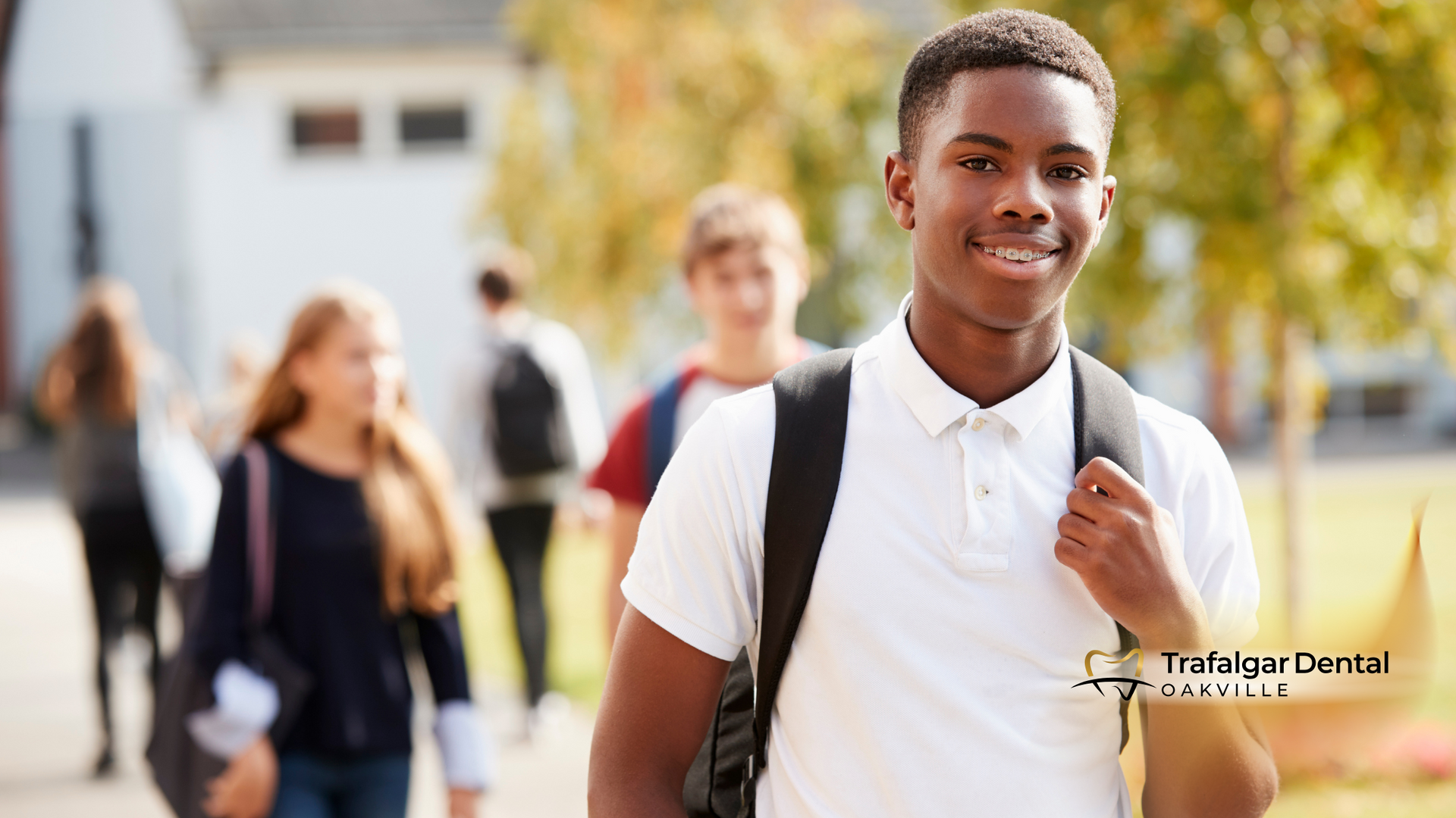 A young man with a backpack is standing in front of a group of people.