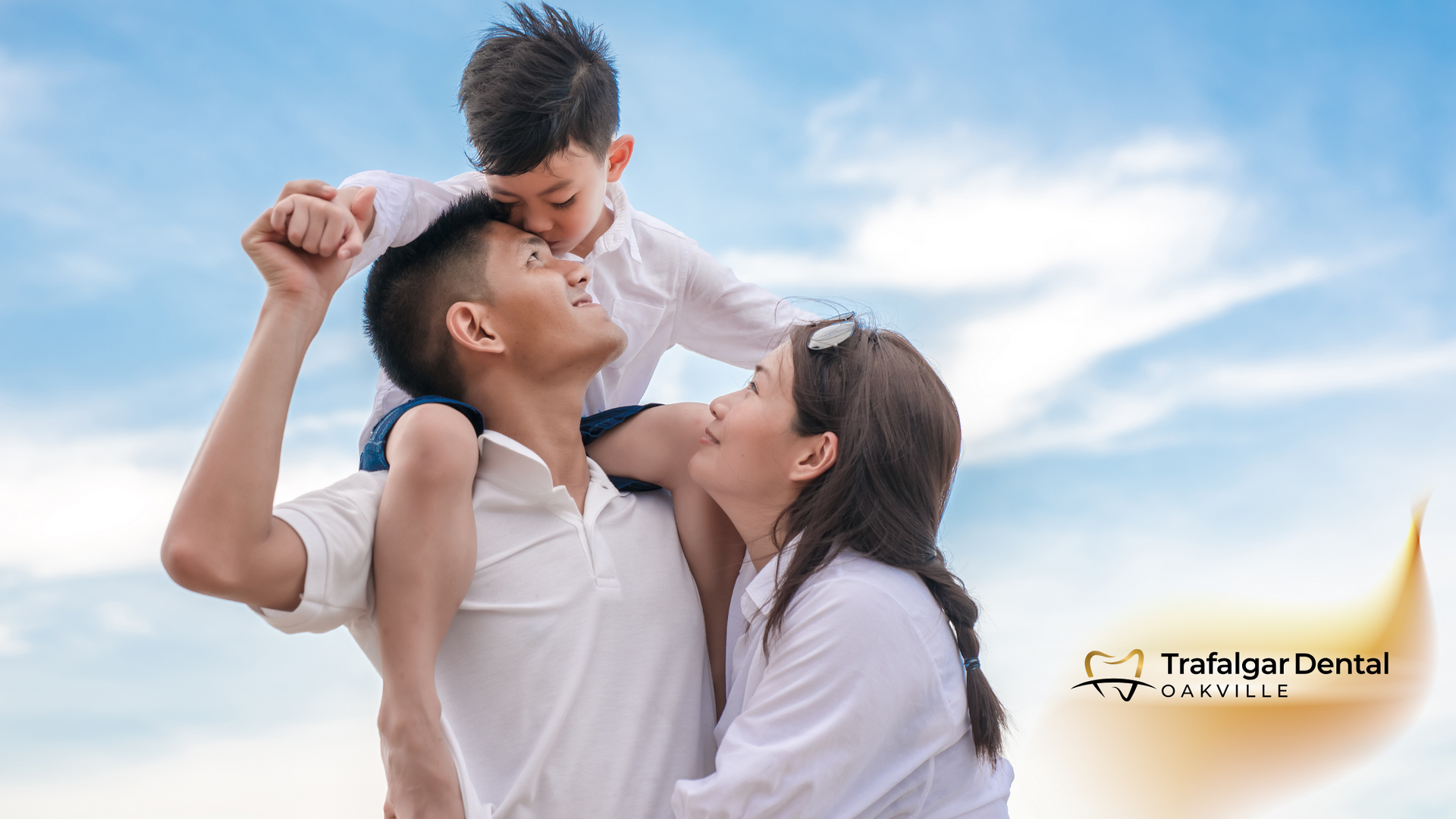 A man and a woman are holding a child on their shoulders.