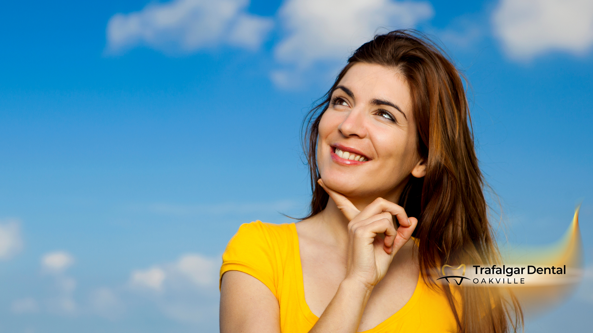 A woman in a yellow shirt is smiling and looking up at the sky.