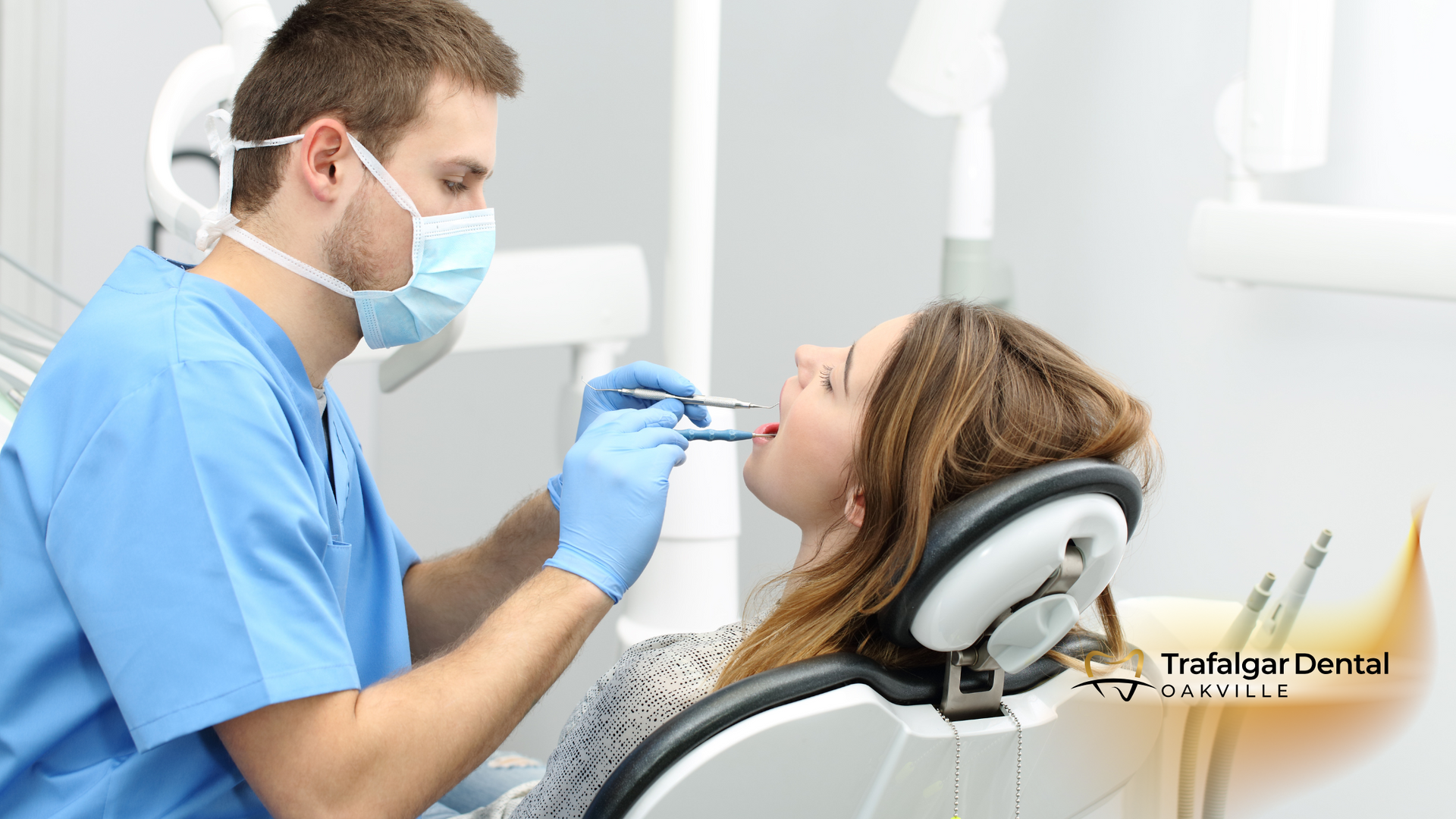 A woman is sitting in a dental chair while a dentist examines her teeth.