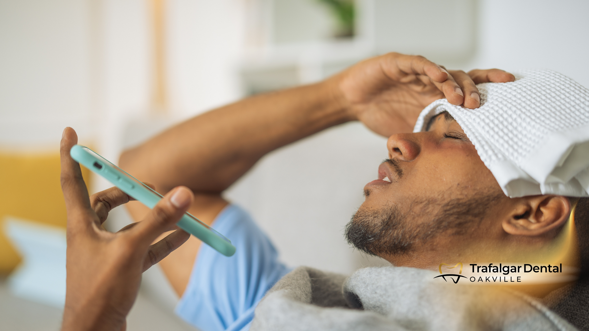 A man with a towel on his head is using a cell phone.
