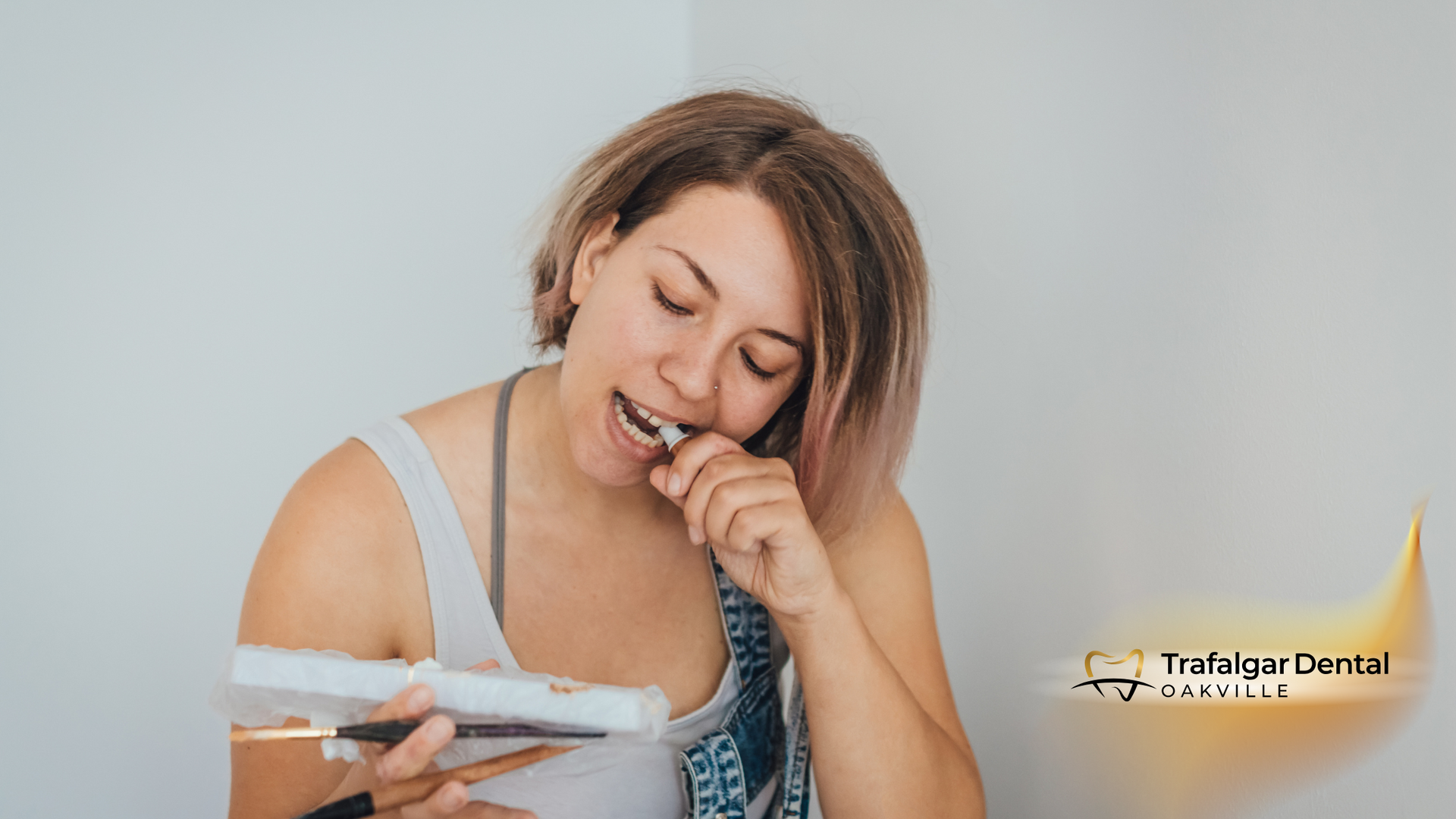 A woman is brushing her teeth with an electric toothbrush.