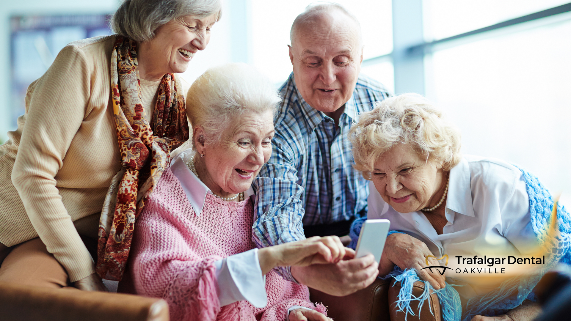 A group of elderly people are looking at a cell phone.