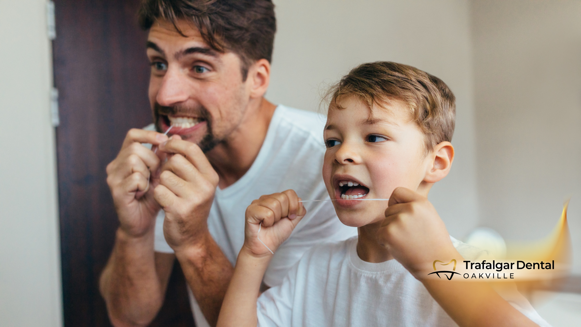 A man and a boy are flossing their teeth in front of a mirror.