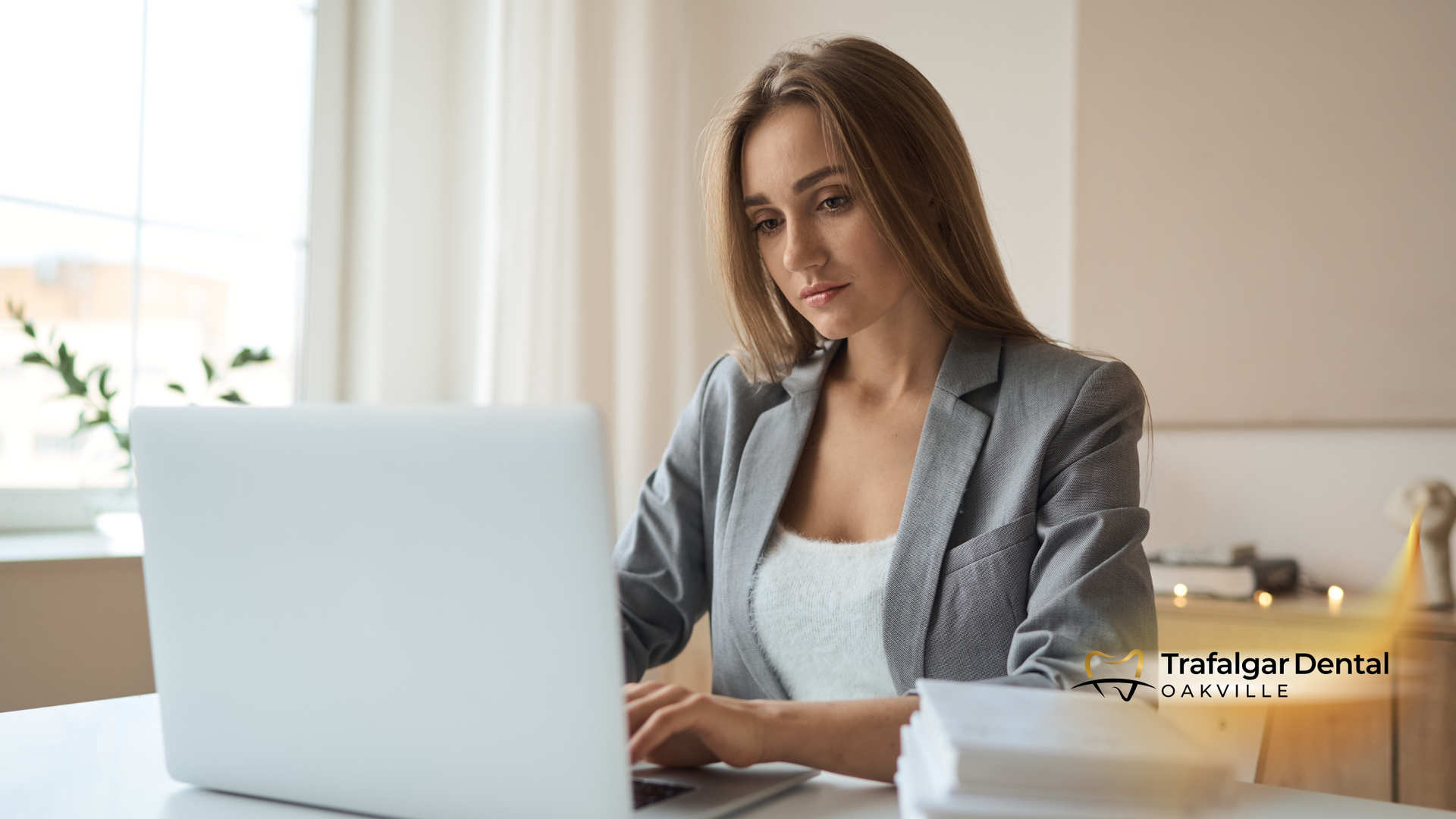 A woman is sitting at a desk using a laptop computer.