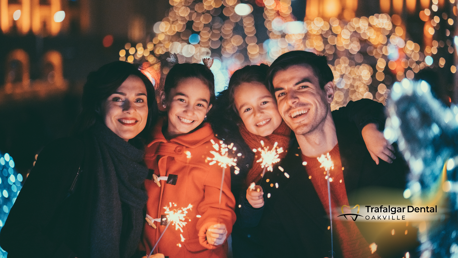 A family is holding sparklers in front of a christmas tree.