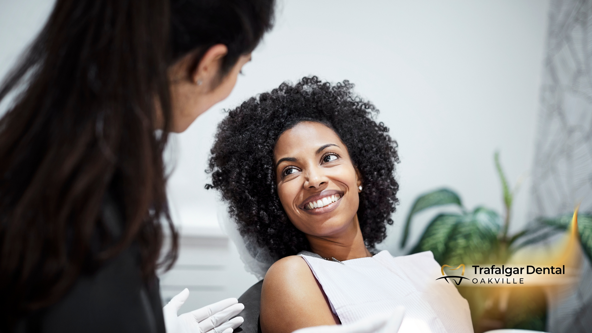 A woman is sitting in a dental chair talking to a dentist.