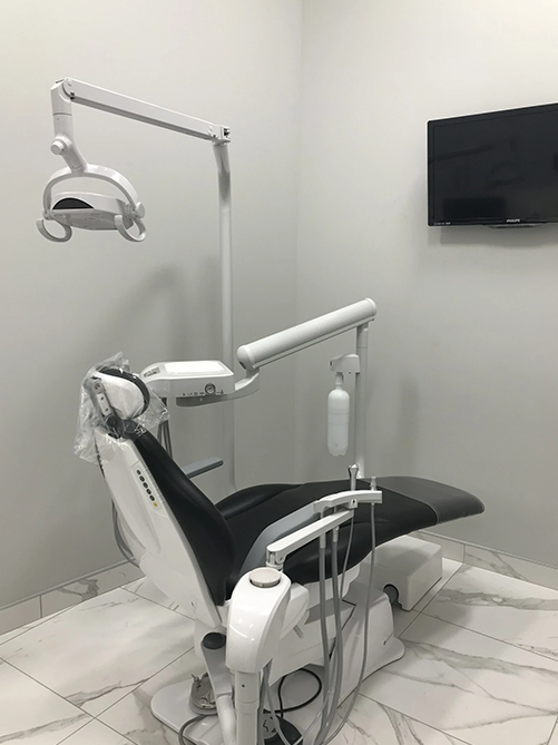 A dental chair is sitting in a dental office next to a television.