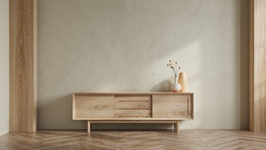 Wooden sideboard against beige wall, two vases with dried flowers, wood-paneled columns, and parquet flooring.