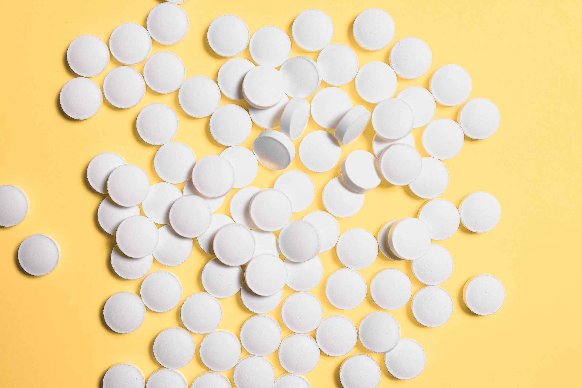 Weisse Schüsslersalztabletten auf einem gelben Hintergrund.