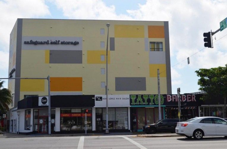 Storage facility with shops below; colorful facade, sunny day, street view.