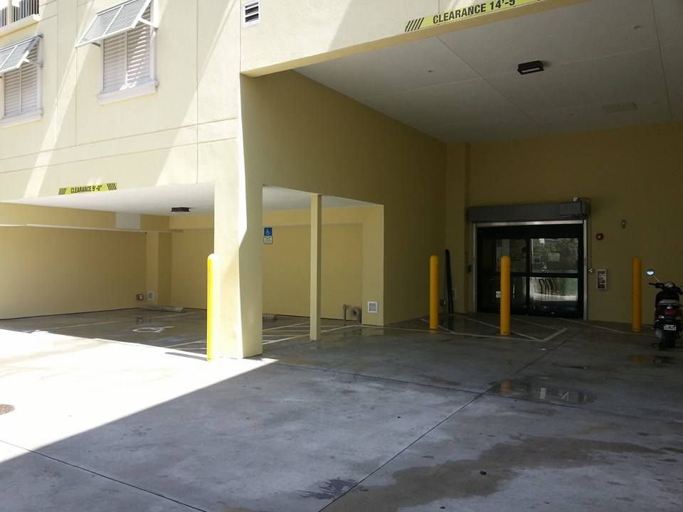 An entrance to a building with a parking garage. A motorcycle is parked to the right.