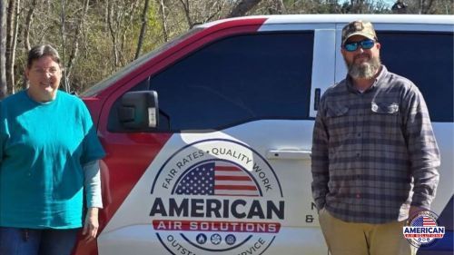 A man and a woman are standing in front of an american air solutions van. A man and a woman are standing in front of an american air solutions van.