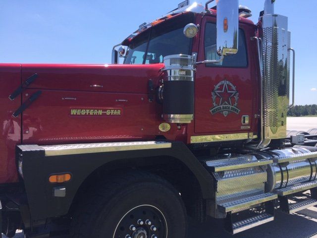 A red semi truck is parked in a parking lot