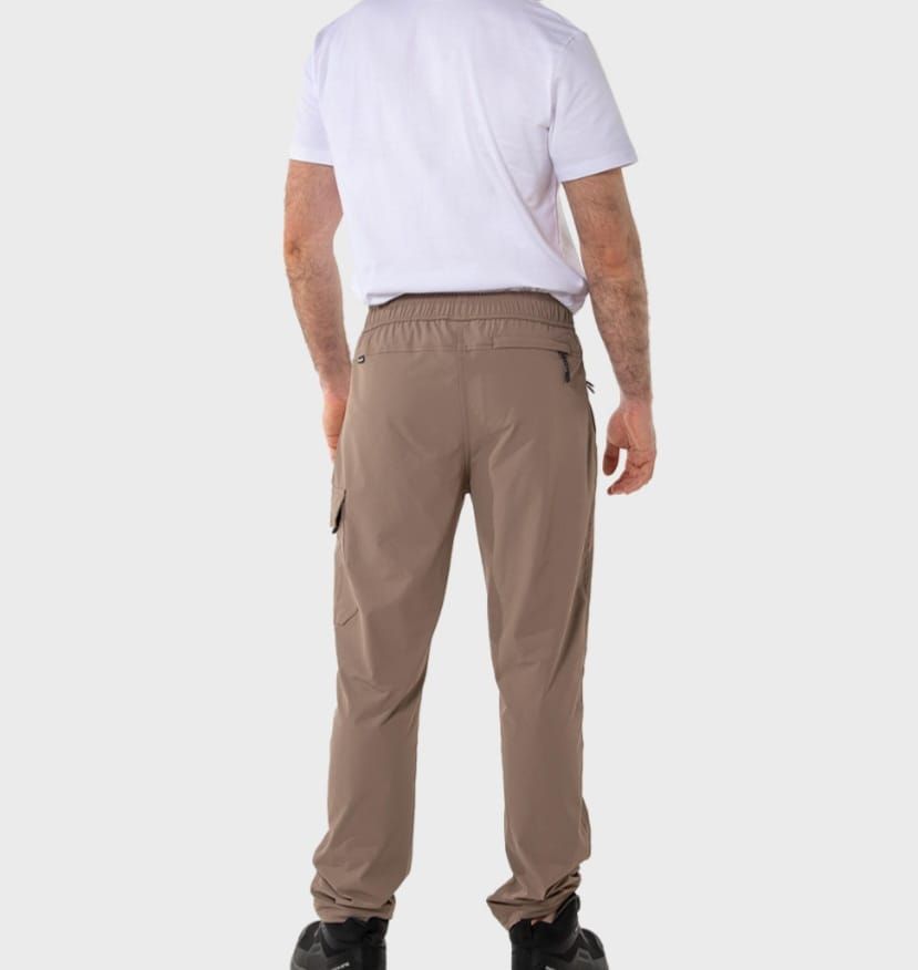 Hombre de pie, vestido con una camiseta blanca estampada y pantalones cargo color beige.