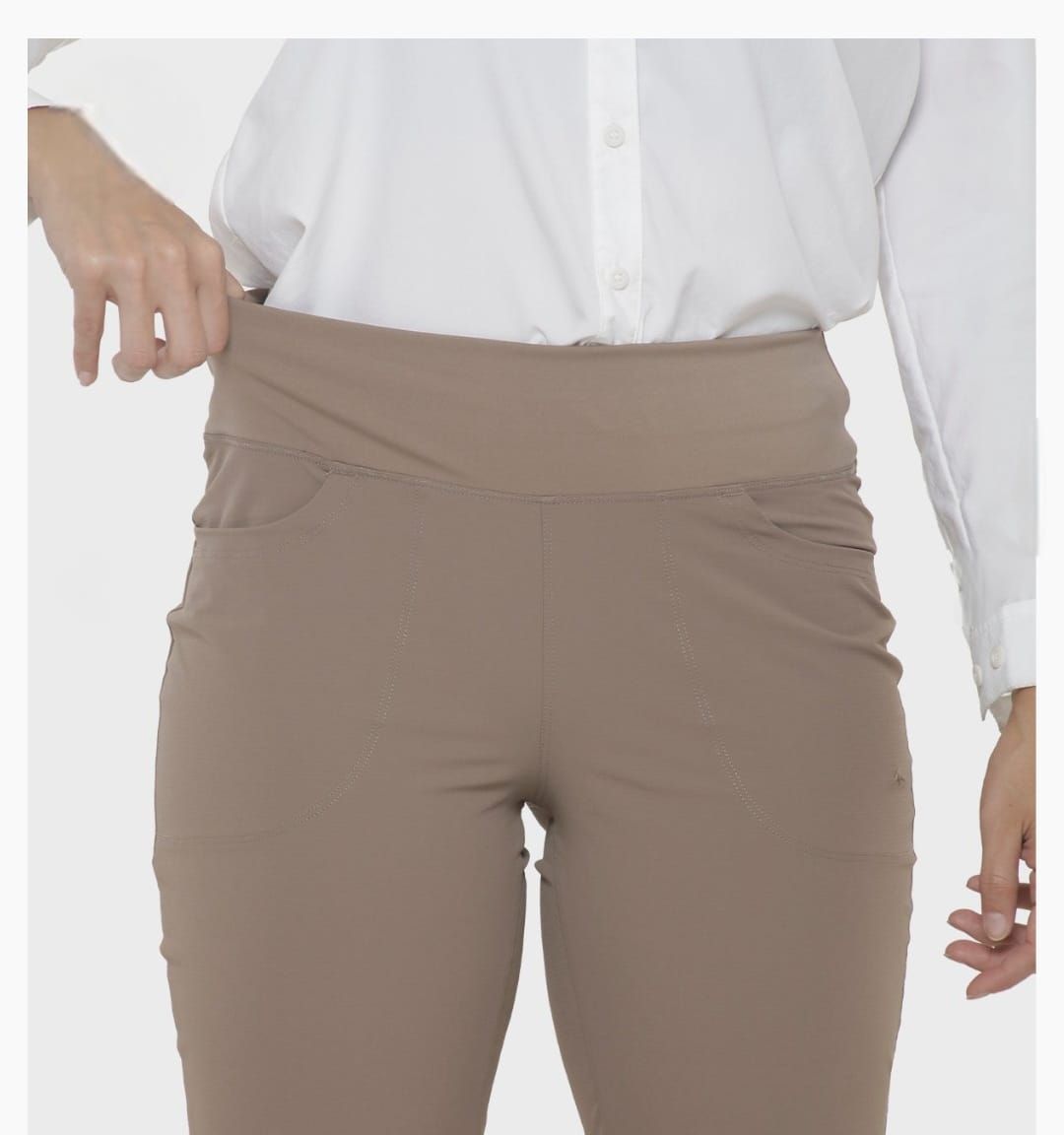 Mujer con pantalones color beige, mano en el bolsillo y camisa blanca.