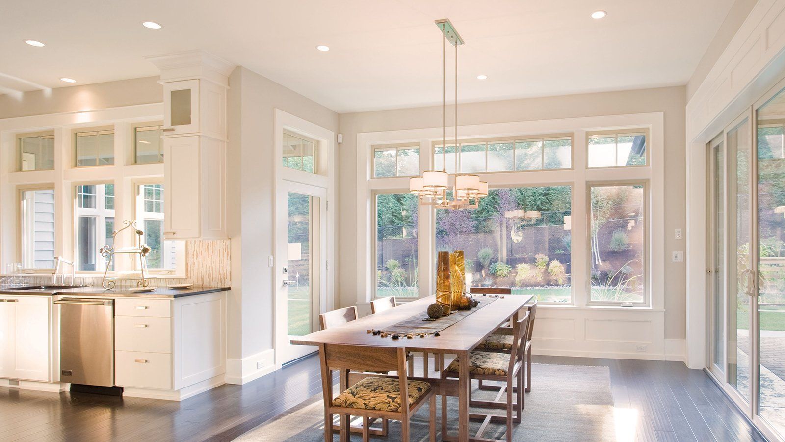 A dining room with a long table and chairs and lots of windows