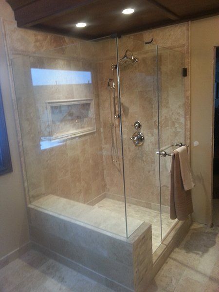 A bathroom with a walk in shower with a glass door