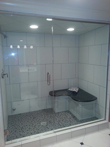 A bathroom with a glass shower door and a bench.