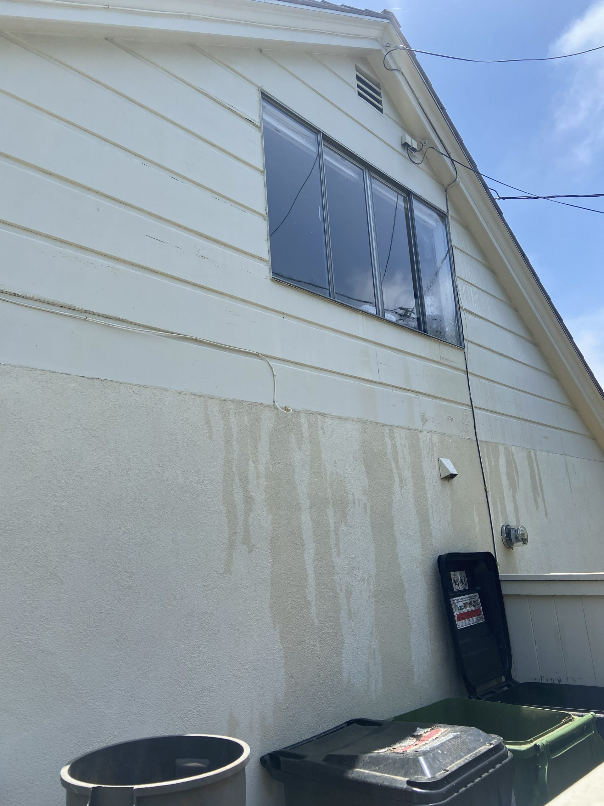 A White House With A Black Trash Can On The Side