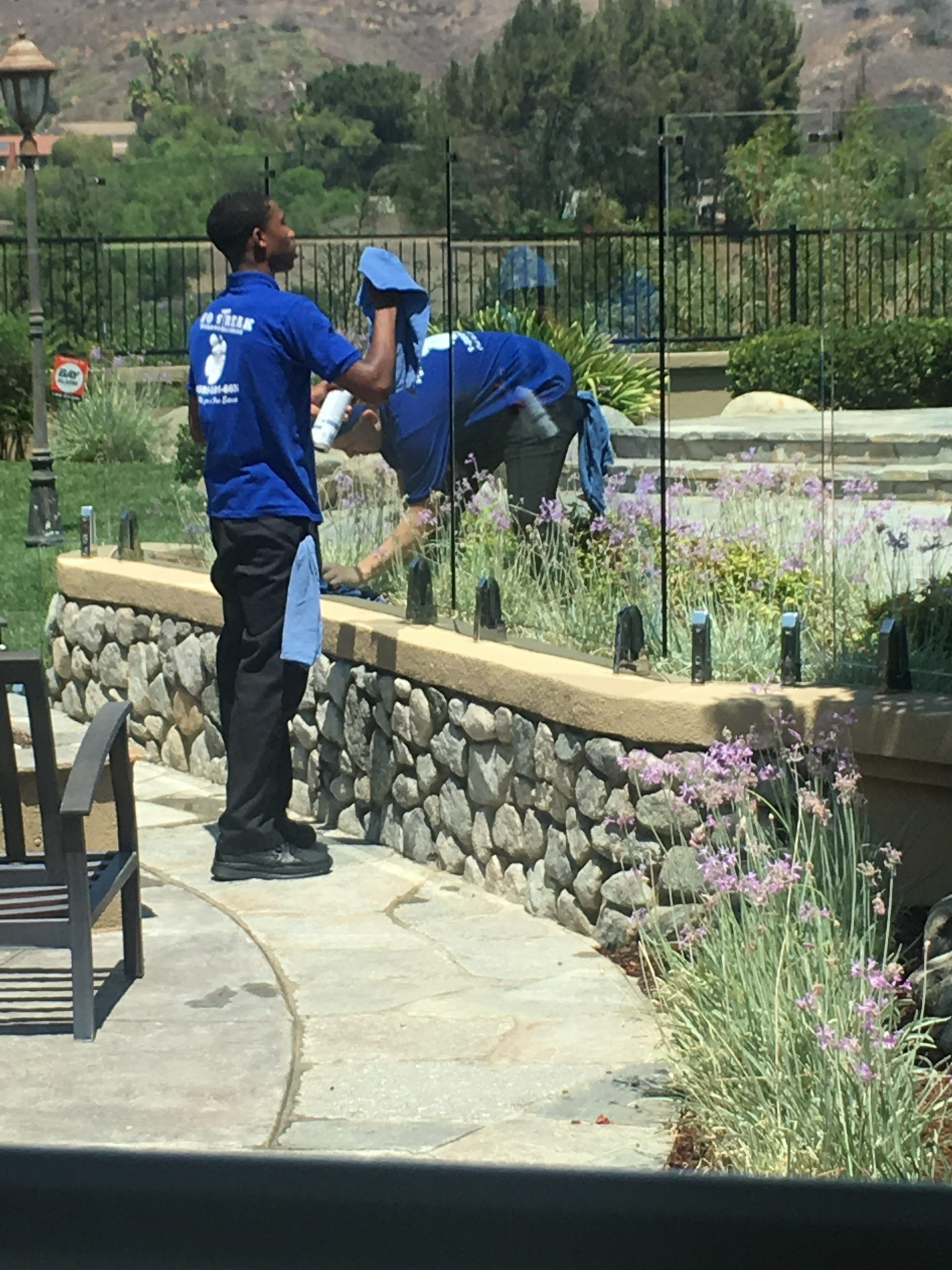 A Man In A Blue Shirt Is Cleaning A Glass Fence