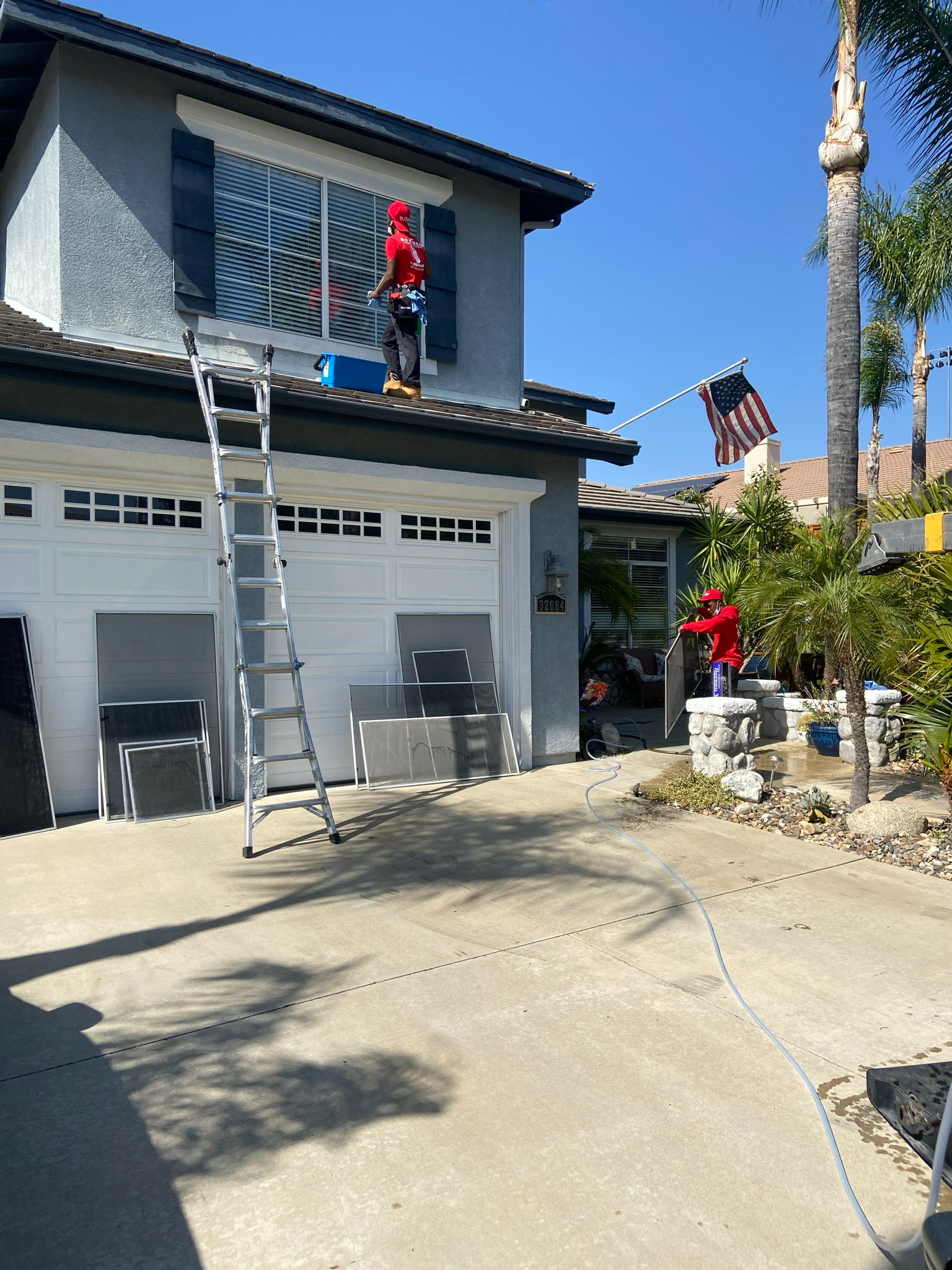 A Man Is Standing On A Ladder On The Roof Of A House