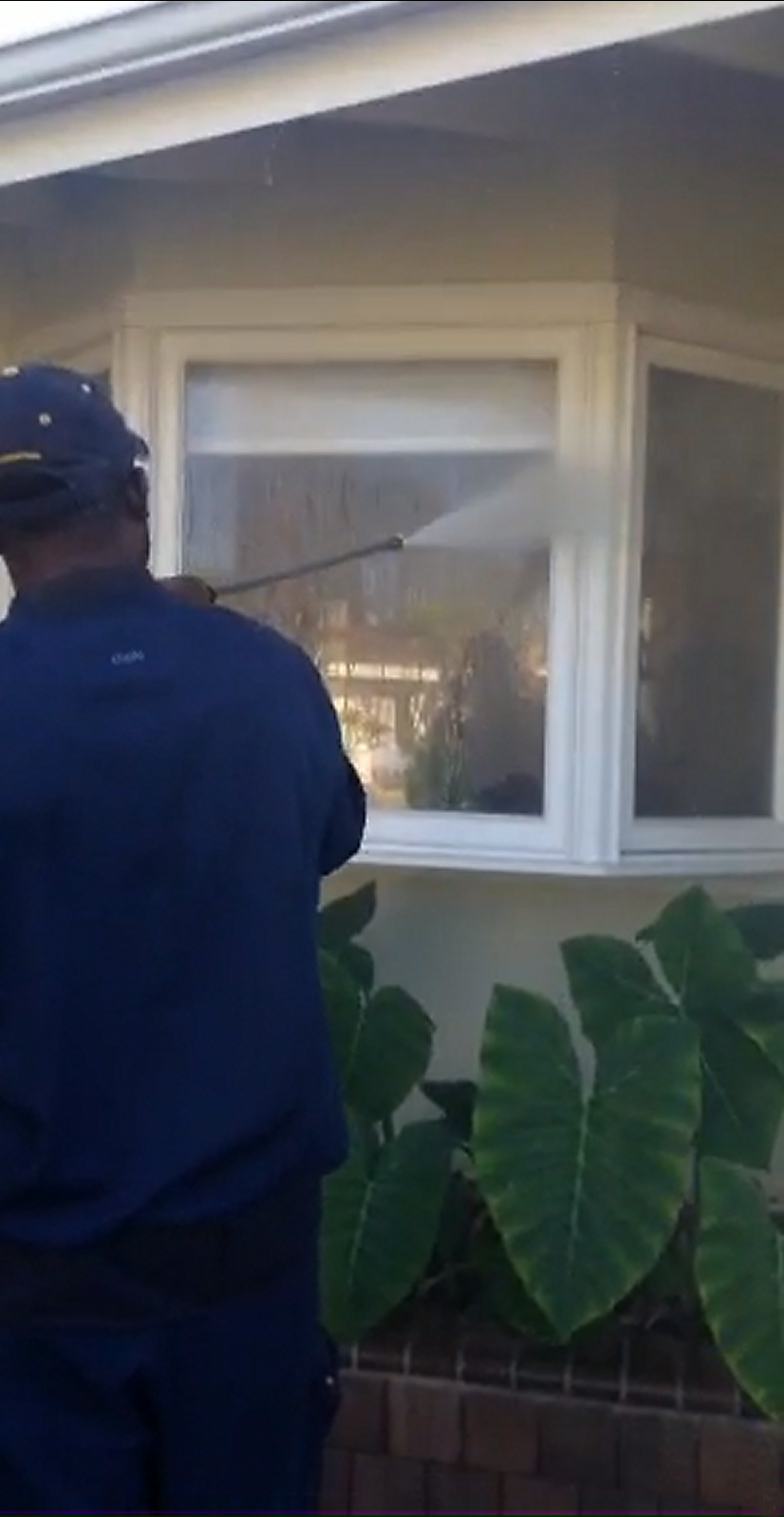 A Man Is Cleaning A Window With A High Pressure Washer