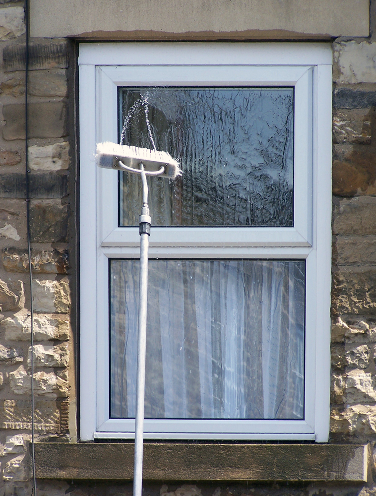 A Window Is Being Cleaned With A Brush On A Pole