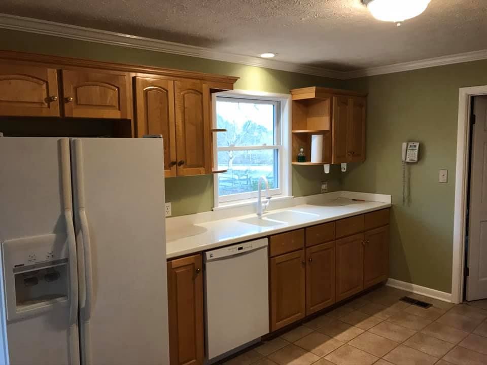 Kitchen with light wood cabinets, white appliances, and green walls.
