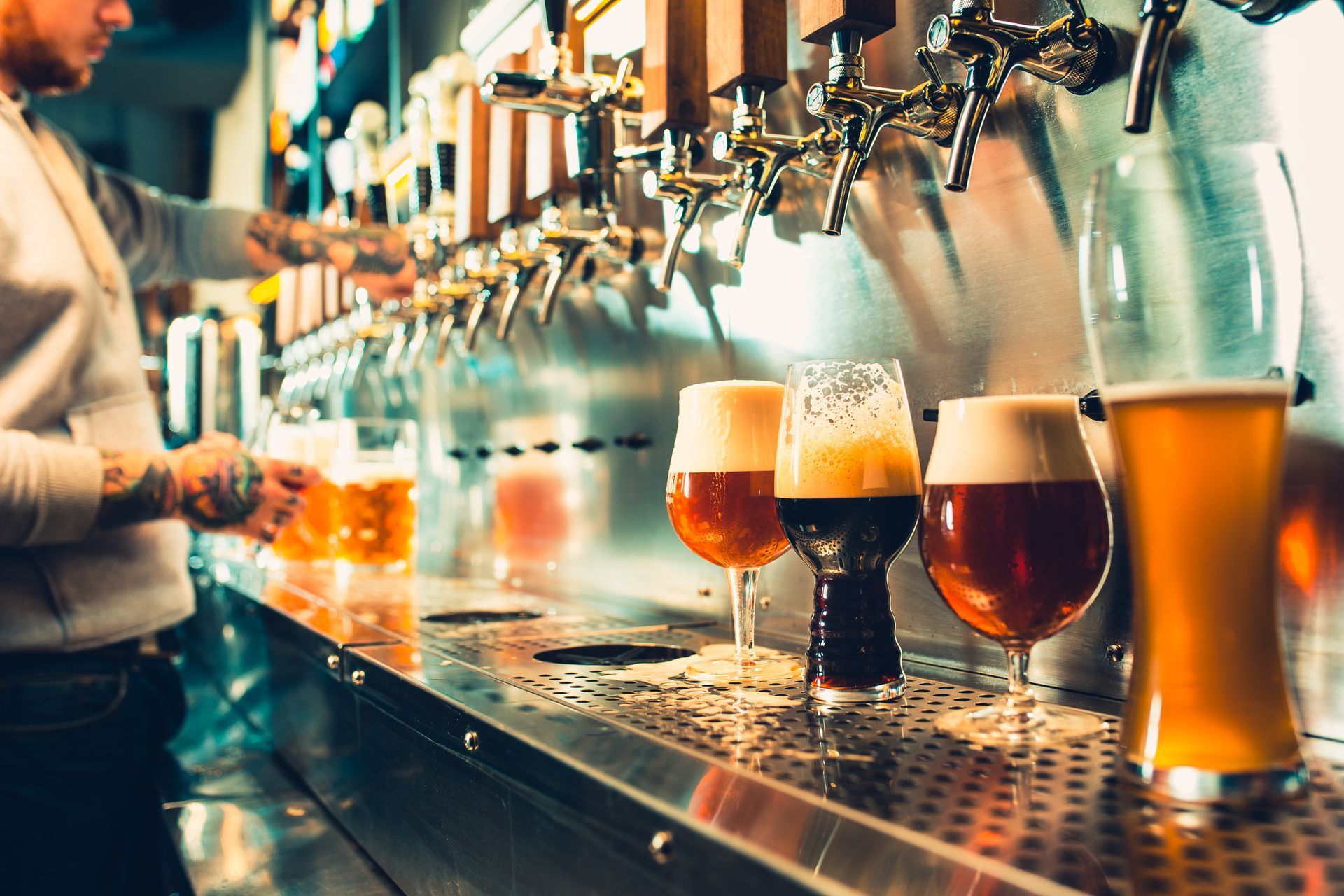 Bartender pouring beer from taps; glasses of various beer styles on a bar.