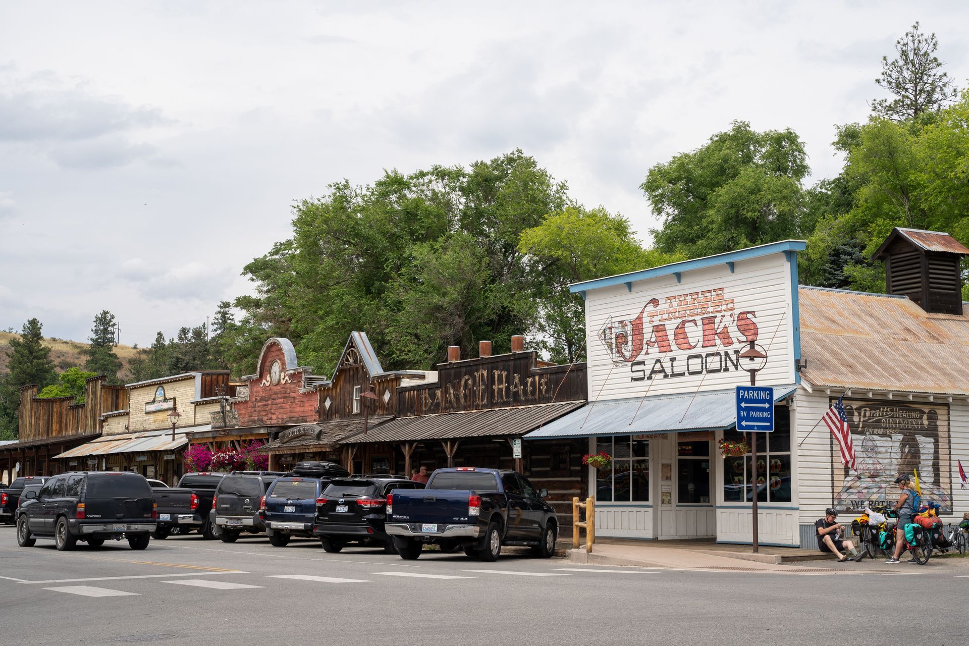 A row of cars are parked in front of a saloon.