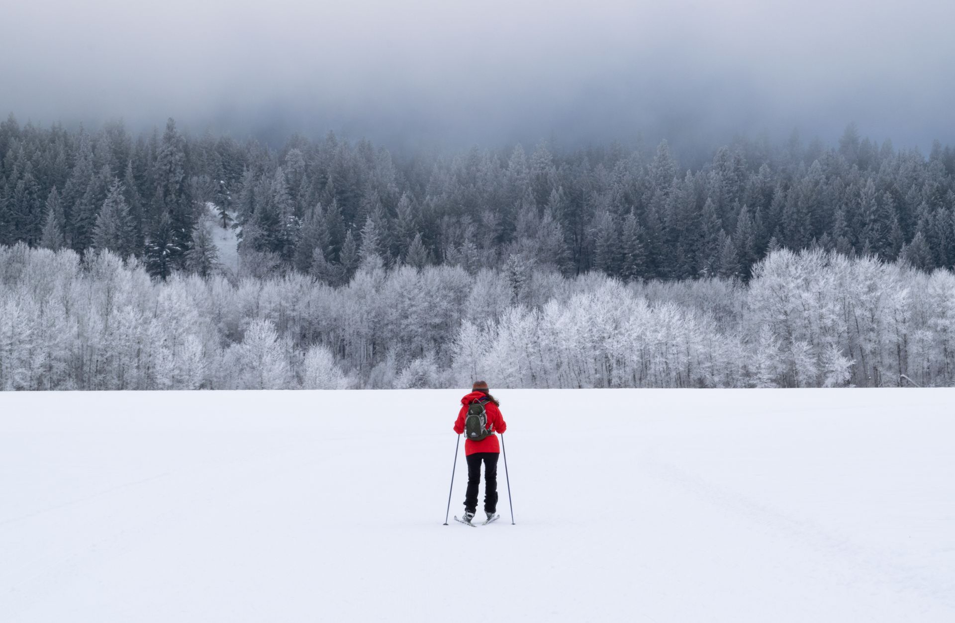 Child skiing on a snowy track, wearing a colorful hat and jacket, in a sunny outdoor setting.