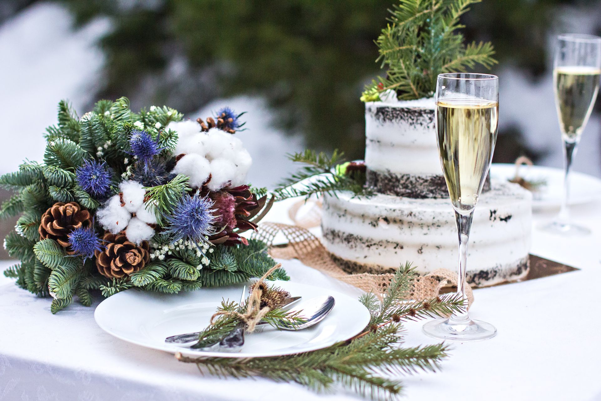 Holiday table setting with pinecone centerpiece, small frosted cake, and champagne flutes