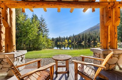 Two wooden chairs are sitting on a porch overlooking a lake.